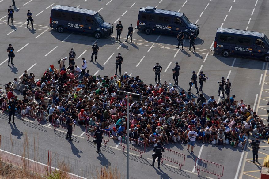 Migrants who crossed from Morocco into Spain are escorted by Spanish police to temporary shelters after being cleared from a beach in the Spanish exlave of Ceuta on Thursday, Aug. 20, 2026. (AP Photo/Antonio Sempere)