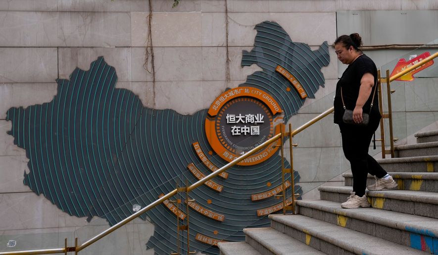 A woman walks by a map showing Evergrande development projects in China, as she heads to an Evergrande city plaza in Beijing on Sept. 18, 2023. (AP Photo/Andy Wong, File)