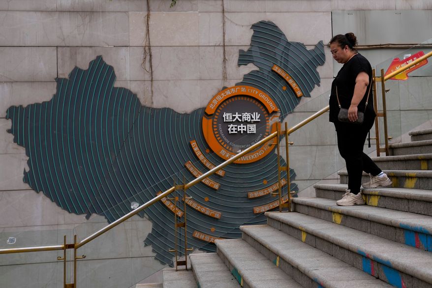A woman walks by a map showing Evergrande development projects in China, as she heads to an Evergrande city plaza in Beijing on Sept. 18, 2023. (AP Photo/Andy Wong, File)