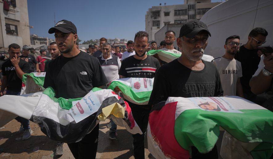 Mourners carry the flag-draped bodies of Palestinians killed in Israeli strikes during the war with Hamas, whose remains were recently recovered from the rubble, in Gaza City, Thursday, Aug. 20, 2026. (AP Photo/Jehad Alshrafi)