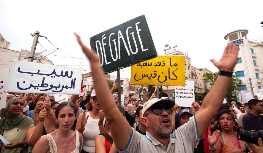 Protesters hold signs with messages that read: "Free the prisoners, No one is happy except President Saied and Where is development? Where is freedom? You have destroyed our purchasing power", during a demonstration against President Kais Saied in downtown Tunis, Tunisia, Saturday, July 25, 2026. (AP Photo/Ons Abid)