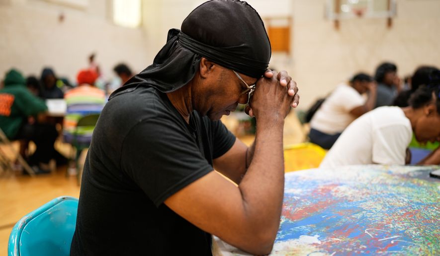 A person prays before receiving a free boxed lunch at City Life Center in Gary, Ind., Thursday, Aug. 20, 2026, more than a week after a deadly storm passed through the area. (AP Photo/Nam Y. Huh)