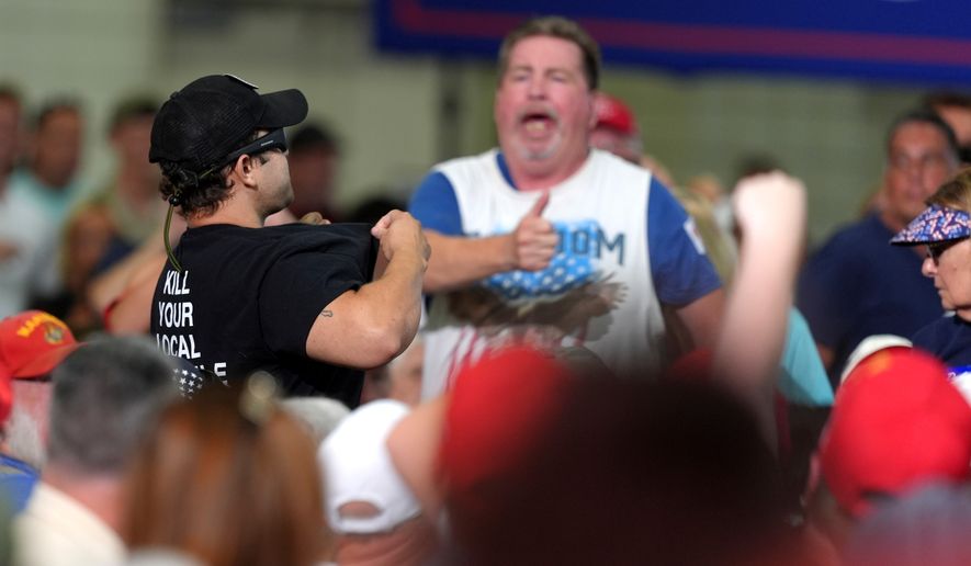 An attendee reacts as a protestor shows off a shirt as President Donald Trump speaks at a campaign rally for Sen. Darline Graham, R-S.C., at the Myrtle Beach Convention Center in Myrtle Beach, S.C., Friday, Aug. 21, 2026. (AP Photo/Jacquelyn Martin)