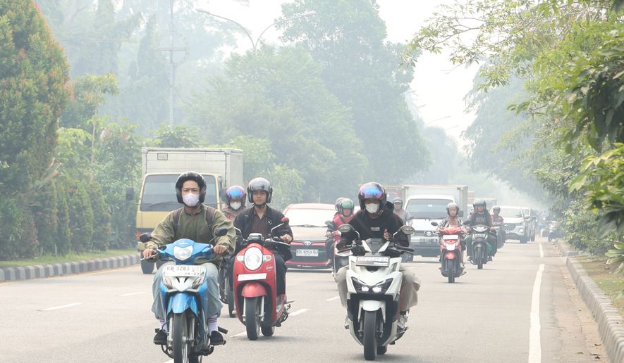 Motorists ride on a road as haze from wildfires blanket the city of Pontianak, West Kalimantan, Indonesia, Friday, Aug. 21, 2026. (AP Photo/Stefanus Taman)