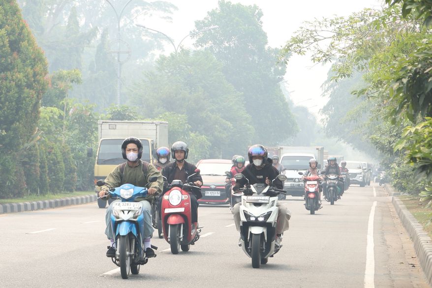 Motorists ride on a road as haze from wildfires blanket the city of Pontianak, West Kalimantan, Indonesia, Friday, Aug. 21, 2026. (AP Photo/Stefanus Taman)