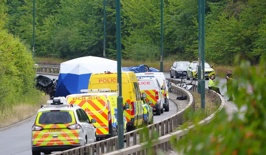 Police officers at the scene of a fatal crash involving a police car and a Volkswagen Passat on the A66 in South Bank, near Middlesbrough, England, Saturday Aug. 22, 2026. (Owen Humphreys/PA via AP)