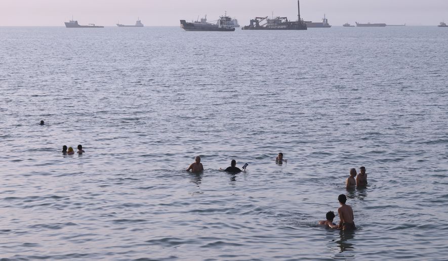 Residents swim as cargo and commercial vessels are anchored in the Strait of Hormuz off Bandar Abbas, Iran, Thursday, Aug. 6, 2026. (Amirhosein Khorgooi/ISNA via AP)