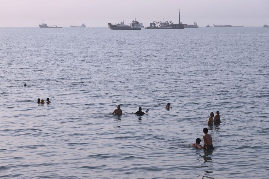 Residents swim as cargo and commercial vessels are anchored in the Strait of Hormuz off Bandar Abbas, Iran, Thursday, Aug. 6, 2026. (Amirhosein Khorgooi/ISNA via AP)