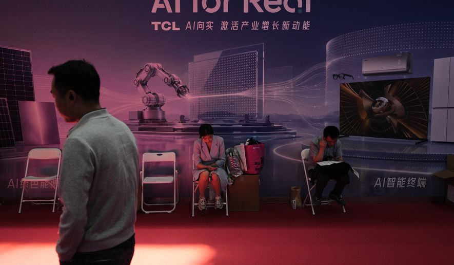 A man walks by as workers rest near a board promoting Artificial Intelligence (AI) at the China International Supply Chain Expo in Beijing on June 25, 2026. (AP Photo/Andy Wong)