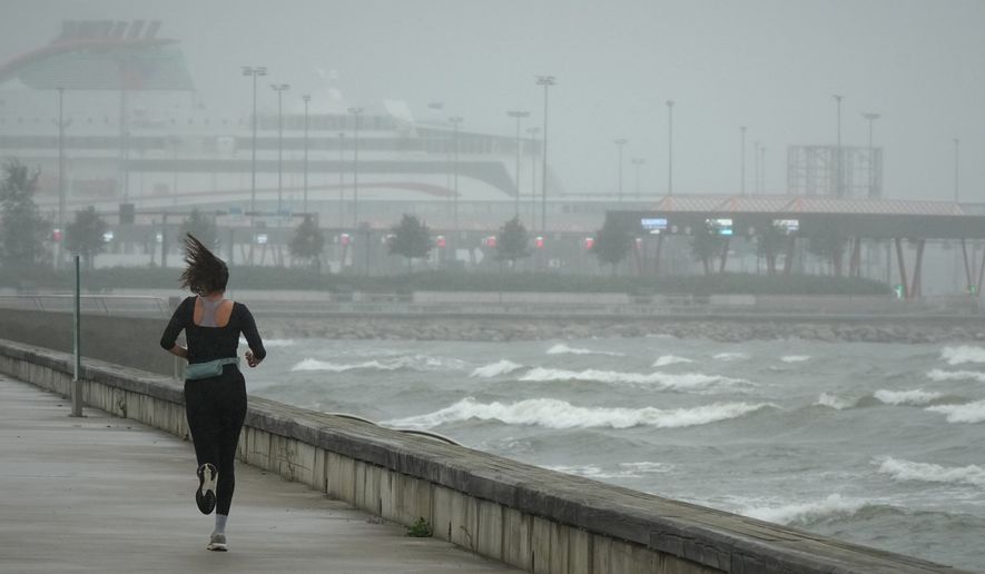 A jogger runs at the beach along the Tallinn bay of the Baltic sea on a rainy and windy day in Tallinn, Estonia, Sunday, Aug. 23, 2026. (AP Photo/Sergei Grits)
