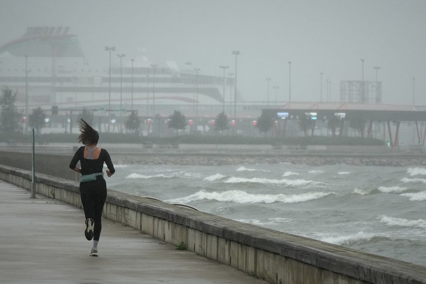 A jogger runs at the beach along the Tallinn bay of the Baltic sea on a rainy and windy day in Tallinn, Estonia, Sunday, Aug. 23, 2026. (AP Photo/Sergei Grits)