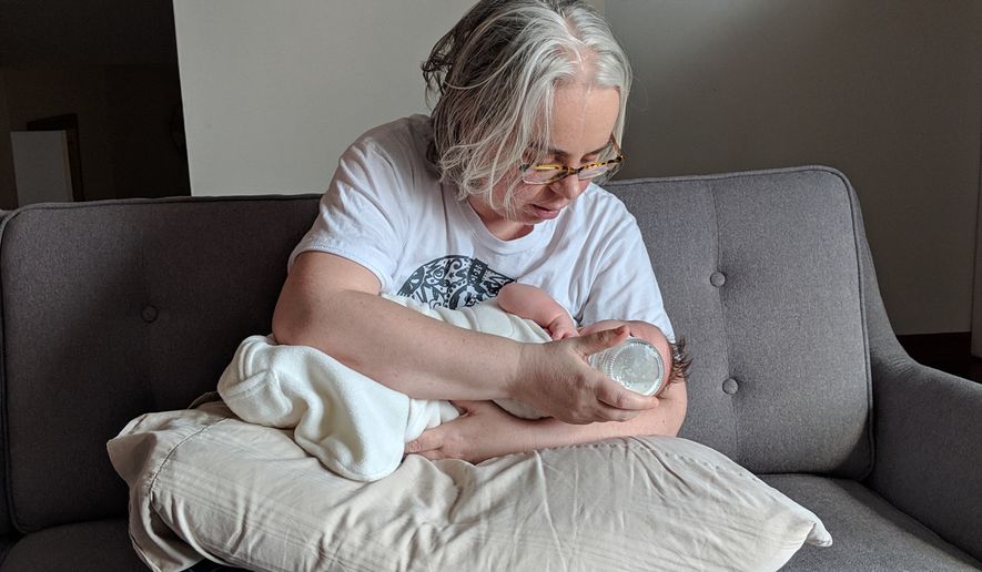This photo provided by James Fitzsimmons shows Bridget María Chesterton cradling her infant daughter on her couch in Grand Island, N.Y., March 20, 2019. (James Fitzsimmons via AP)