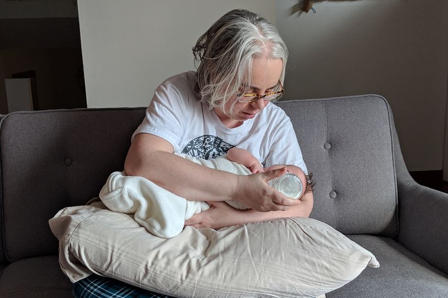 This photo provided by James Fitzsimmons shows Bridget María Chesterton cradling her infant daughter on her couch in Grand Island, N.Y., March 20, 2019. (James Fitzsimmons via AP)