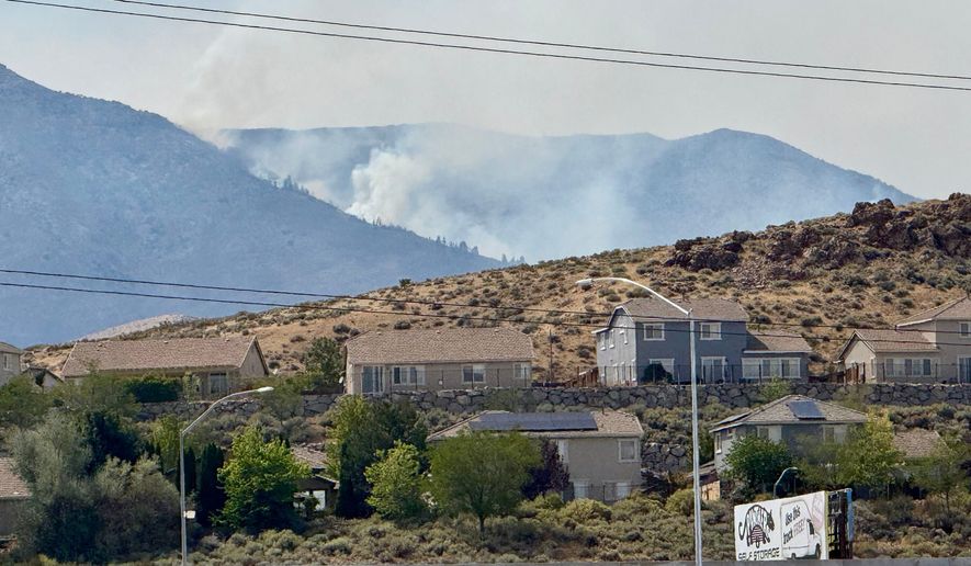 Smoke billows in the distance as a wildfire burns in Reno, Nev., Sunday, August 23, 2026. (AP Photo/Haven Daley)