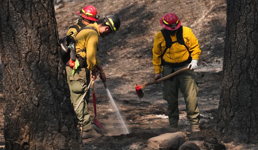 A crew does mop-up work in a burned area of Wyakin Park after a wildfire hit the northern part of Spokane, Wash., Tuesday, Aug. 4, 2026. (AP Photo/Lindsey Wasson)