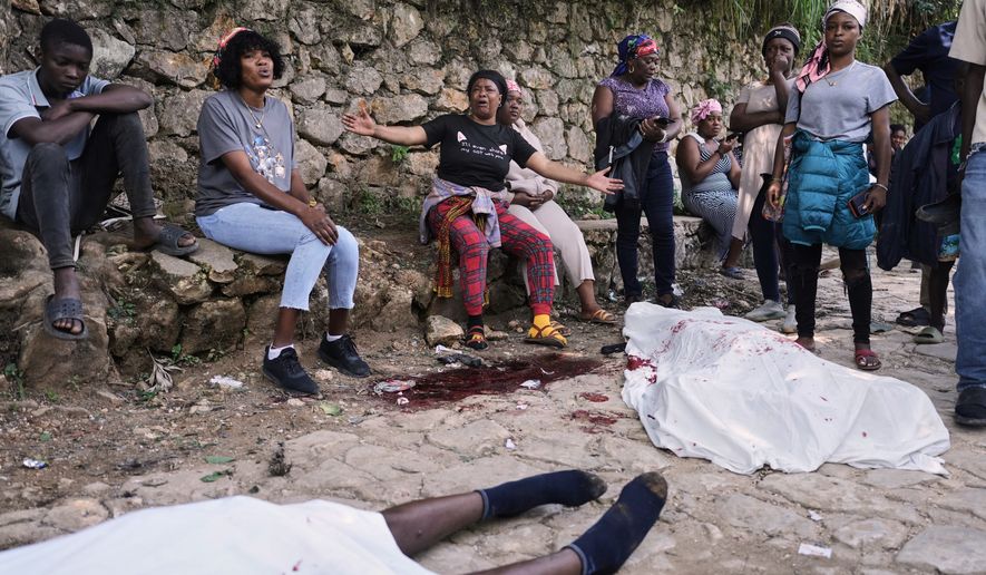 People gather next to the bodies of people they said were their relatives and were killed in a gang attack in the Kenscoff neighborhood of Port-au-Prince, Haiti, Monday, Aug. 24, 2026. (AP Photo/Odelyn Joseph)
