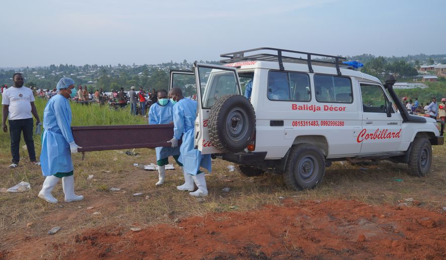 People dressed in protective gear unload a coffin containing the remains of six-year-old Baudjo Baraka Jules, who died of Ebola, for a burial service in Bunia, Ituri province, eastern Congo, Tuesday, Aug. 18, 2026. (AP Photo/Dieudonne Dirole)