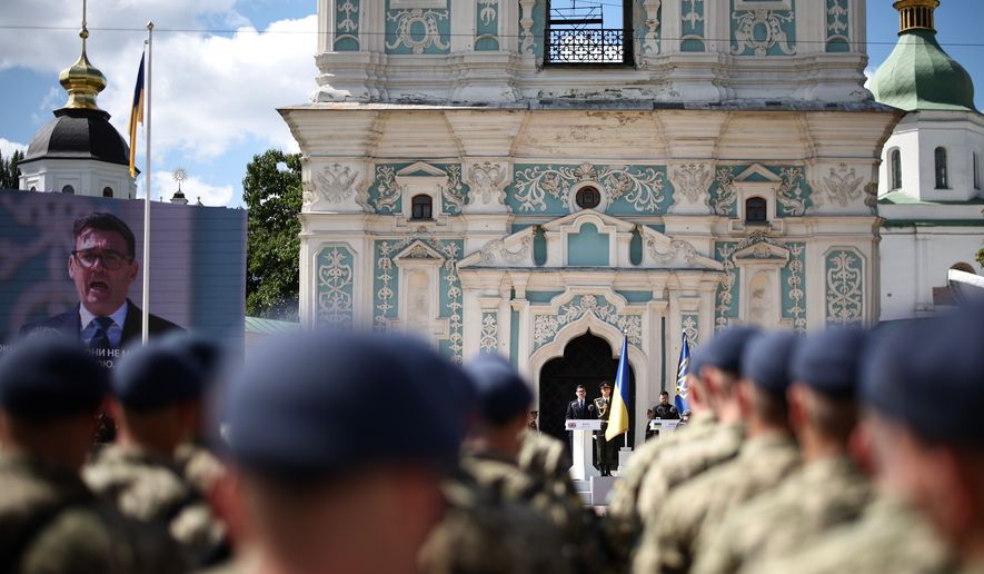 Britain's Prime Minister Andy Burnham, center, appears also on a giant screen, left, as National Guard of Ukraine and European leaders attend a commemorative ceremony marking Ukraine's 35th Independence Day outside St. Sofia Cathedral in Kyiv, Ukraine, Monday, Aug. 24, 2026. (Henry Nicholls/Pool Photo via AP)