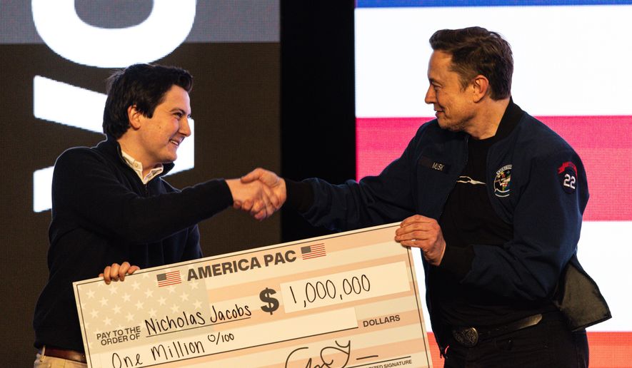 Elon Musk hands over a million-dollar check to Nicholas Jacobs during a town hall in Green Bay, Wis., on March 30, 2025. (AP Photo/Jeffrey Phelps) **FILE**