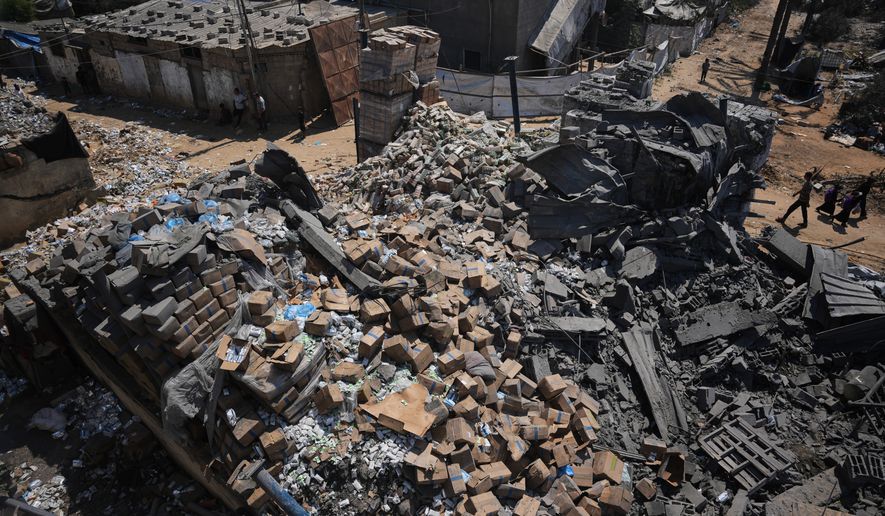 Palestinians walk past a food-aid warehouse damaged in an Israeli airstrike that targeted a nearby house in Deir al-Balah, central Gaza Strip, Wednesday, Aug. 26, 2026. (AP Photo/Abdel Kareem Hana)