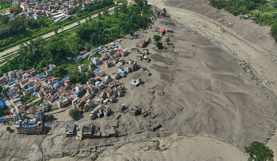 Damaged houses stand precariously near the swollen, debris-choked banks of the Trishuli River after flash floods in Nepal's Nuwakot district on Wednesday, Aug. 26, 2026. (AP Photo/Niranjan Shrestha)