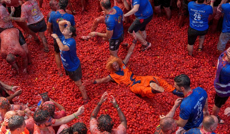 Revelers throw tomatoes at each other during the annual "Tomatina" tomato fight fiesta, in the village of Bunol near Valencia, Spain, Wednesday, Aug. 26, 2026. (AP Photo/Alberto Saiz)