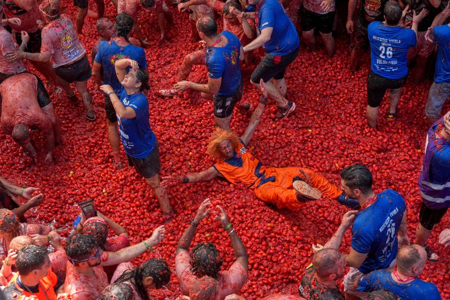 Revelers throw tomatoes at each other during the annual "Tomatina" tomato fight fiesta, in the village of Bunol near Valencia, Spain, Wednesday, Aug. 26, 2026. (AP Photo/Alberto Saiz)