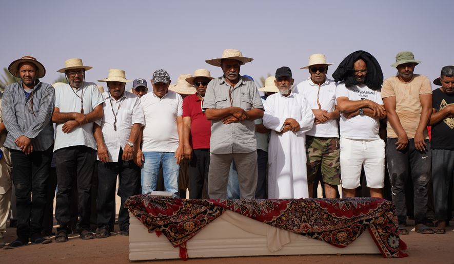 People perform prayers in Ben Guerdane, Tunisia, Wednesday, Aug. 26, 2026, before a burial for migrants who drowned at sea after their boat capsized off the country's southeastern coast. (AP Photo/Bassem Aouini)