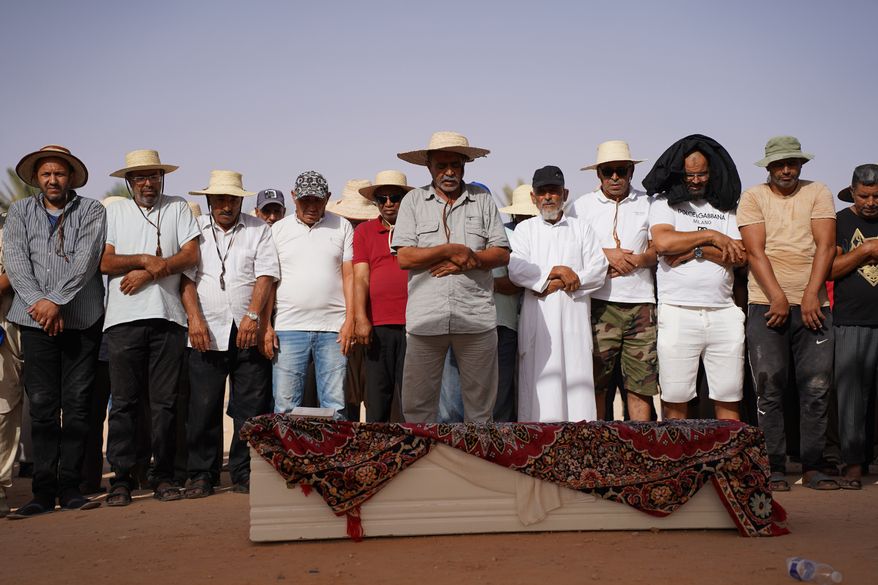 People perform prayers in Ben Guerdane, Tunisia, Wednesday, Aug. 26, 2026, before a burial for migrants who drowned at sea after their boat capsized off the country's southeastern coast. (AP Photo/Bassem Aouini)