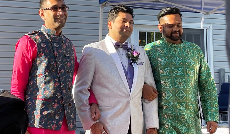 This photo provided by Jolene Gosha shows Venus Patel, left, walking his friend, Pratik Jhaveri, center, down the wedding aisle in Collinsville, Ill., June 18, 2022. CORRECTION: Corrects Jolene's surname from Gosh to Gosha. (Jolene Gosha via AP)