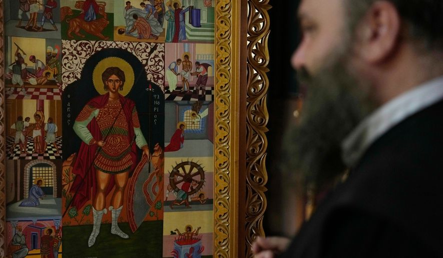 Father Nikolaos Vlavianos stands beside an icon of Saint Fanourios, known in Greek as "The Revealer," at the Church of St. Fanourios in Athens, Tuesday, Aug. 25, 2026. (AP Photo/Thanassis Stavrakis)