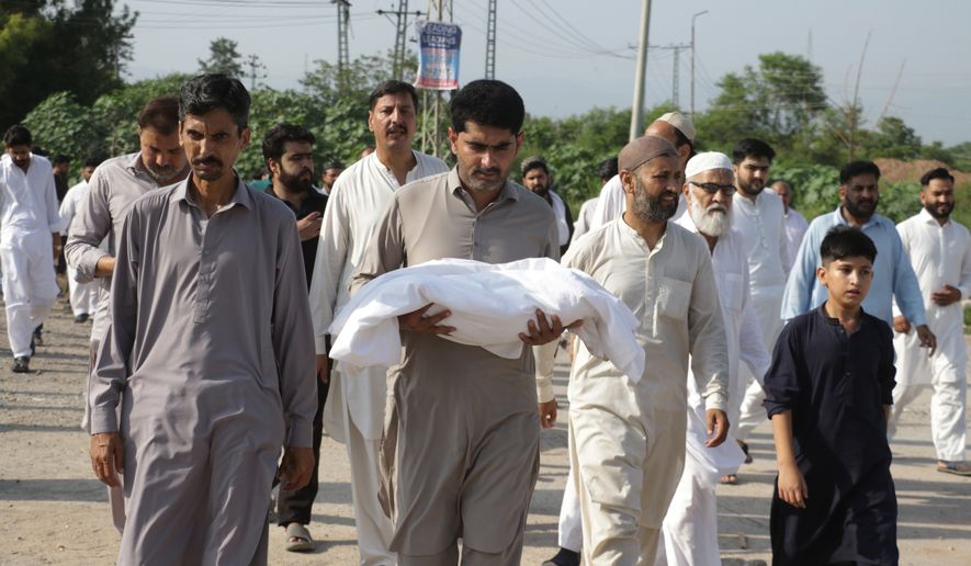 A man carries the body of a newborn for burial after the child died in a fire at a hospital in Islamabad, Pakistan, Wednesday, Aug. 26, 2026. (AP Photo/Ehsan Shahzad)