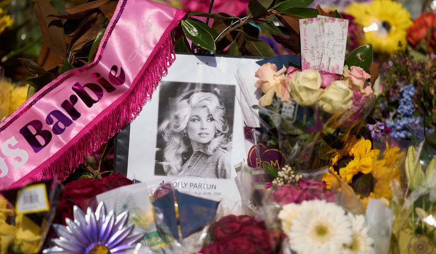 A portrait of the late Dolly Parton surrounded by flowers and cards in a memorial sits outside her home Thursday, Aug. 27, 2026, in Brentwood, Tenn. (AP Photo/George Walker IV)