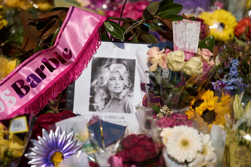 A portrait of the late Dolly Parton surrounded by flowers and cards in a memorial sits outside her home Thursday, Aug. 27, 2026, in Brentwood, Tenn. (AP Photo/George Walker IV)