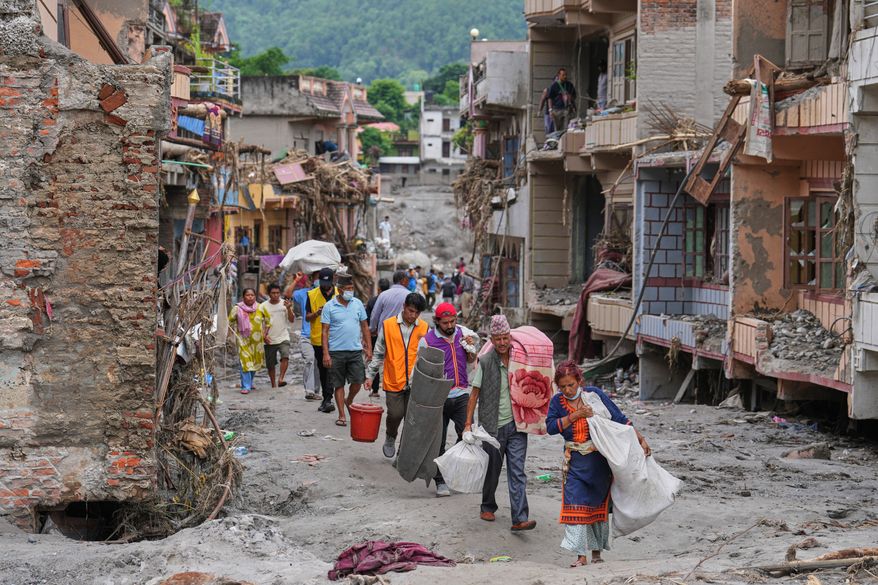 Residents carry their belongings salvaged from their damaged homes filled with mud and debris in Devighat, in Nepal's Nuwakot district, Saturday, Aug. 29, 2026, following the Aug. 26 flash floods. (AP Photo/Rajesh Kumar Singh)