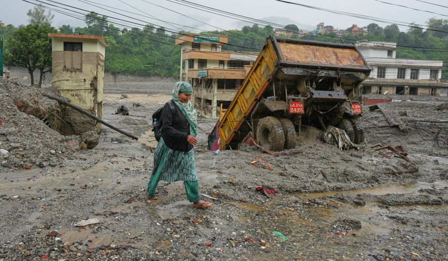 A woman walks through mud and debris left behind by flash flooding in Nepal's Nuwakot district, Saturday, Aug. 29, 2026. (AP Photo/Rajesh Kumar Singh)