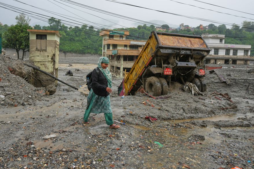 A woman walks through mud and debris left behind by flash flooding in Nepal's Nuwakot district, Saturday, Aug. 29, 2026. (AP Photo/Rajesh Kumar Singh)