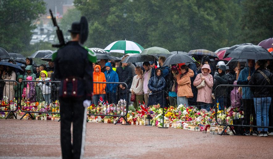 Mourners gather in the pouring rain to watch as King Harald V's remains arrive to the Royal Palace in Oslo, Norway, Friday, Aug. 28, 2026. (Heiko Junge/NTB via AP)