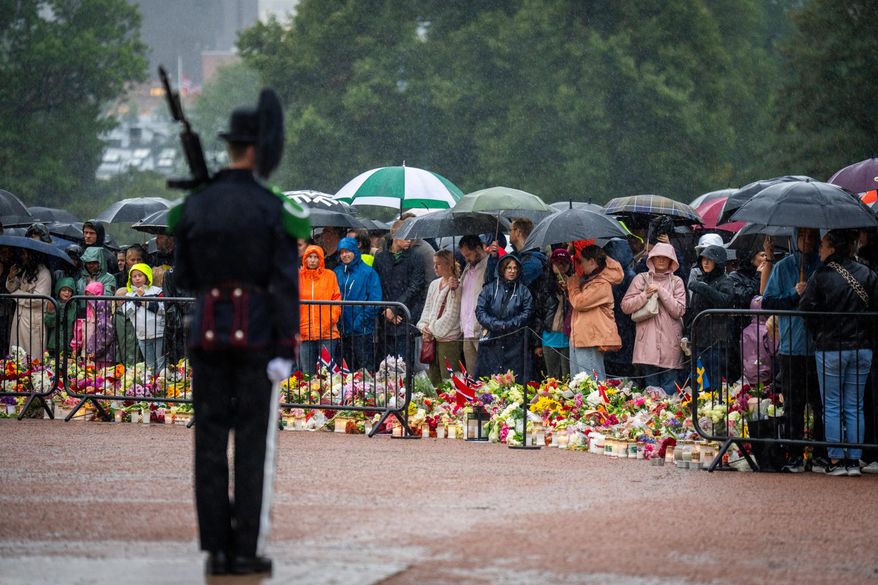 Mourners gather in the pouring rain to watch as King Harald V's remains arrive to the Royal Palace in Oslo, Norway, Friday, Aug. 28, 2026. (Heiko Junge/NTB via AP)