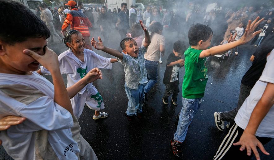 Children laugh and play in a spray of water during a street celebration marking Prophet Muhammad's birthday in Tehran, Iran, Sunday, Aug. 30, 2026. (AP Photo/Vahid Salemi)