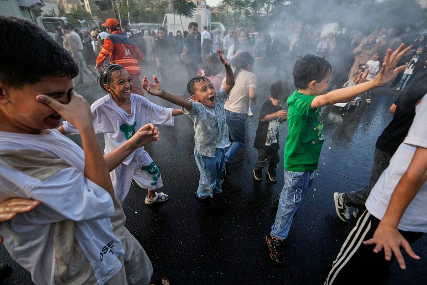 Children laugh and play in a spray of water during a street celebration marking Prophet Muhammad's birthday in Tehran, Iran, Sunday, Aug. 30, 2026. (AP Photo/Vahid Salemi)