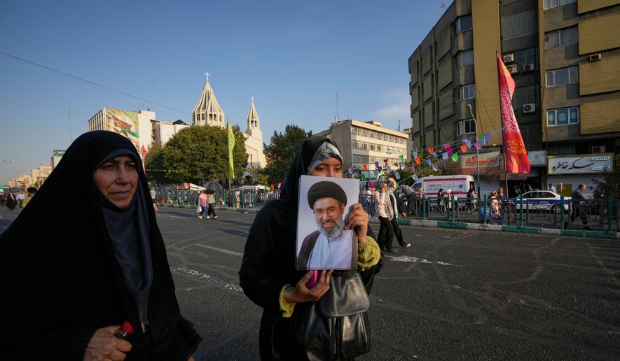 A government supporter holds a portrait of Iran's Supreme Leader Mojtaba Khamenei during a street celebration marking Prophet Muhammad's birthday, with St. Sarkis Armenian Cathedral in the background, in Tehran, Iran, Sunday, Aug. 30, 2026. (AP Photo/Vahid Salemi)
