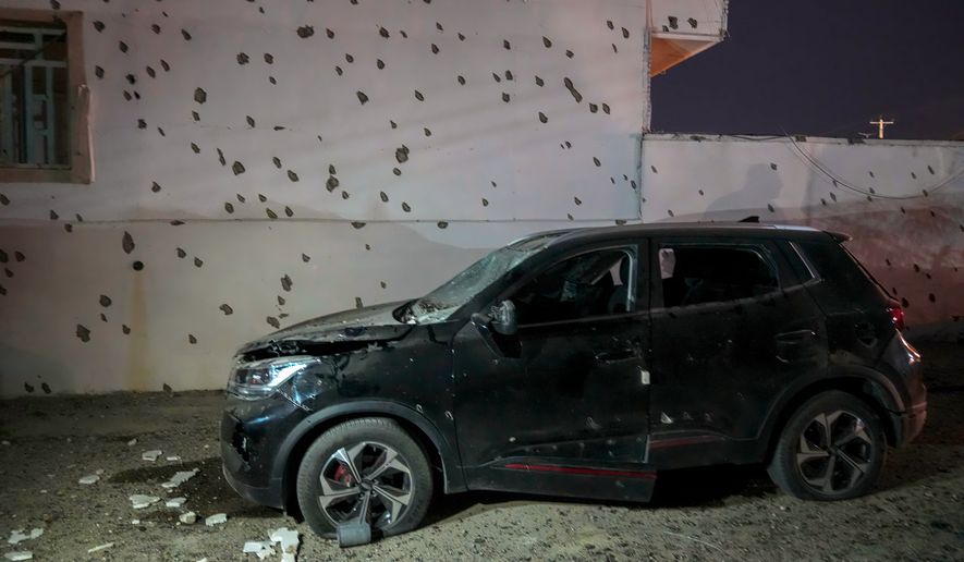 A damaged car sits beside a wall bearing numerous impact marks near the site of a strike in Lamerd, southern Iran, Saturday, Feb. 28, 2026. (Alireza Ameri/Tasnim News Agency via AP)