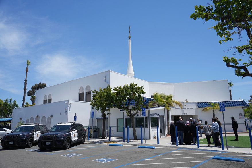 People gather as police vehicles are parked outside of the Islamic Center of San Diego, the day after a shooting, May 19, 2026, in San Diego. (AP Photo/Jae C. Hong, File)