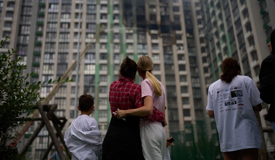 Locals watch as firefighters work after a Russian drone attack struck a residential building in Kyiv, Tuesday, Sept. 1, 2026. (AP Photo/Francisco Seco)