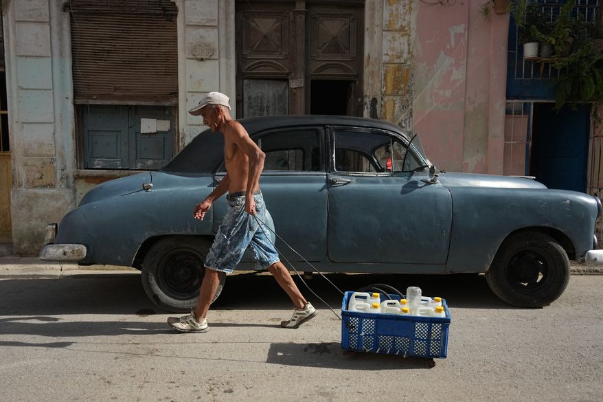 A man pulls a cart carrying drinking water during a power outage in Havana, Cuba, Monday, Aug. 3, 2026. (AP Photo/Ramon Espinosa)