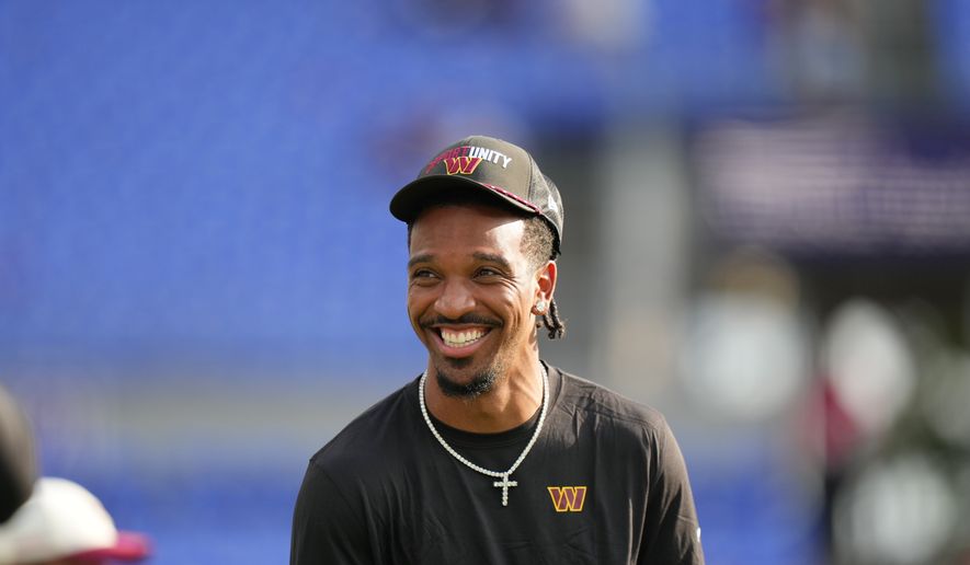 Washington Commanders quarterback Jayden Daniels smiles while watching warmups before an NFL preseason football game against the Baltimore Ravens, Friday, Aug. 28, 2026, in Baltimore. (AP Photo/Stephanie Scarbrough)
