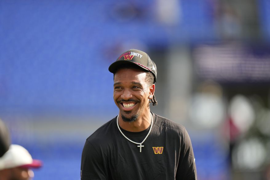 Washington Commanders quarterback Jayden Daniels smiles while watching warmups before an NFL preseason football game against the Baltimore Ravens, Friday, Aug. 28, 2026, in Baltimore. (AP Photo/Stephanie Scarbrough)