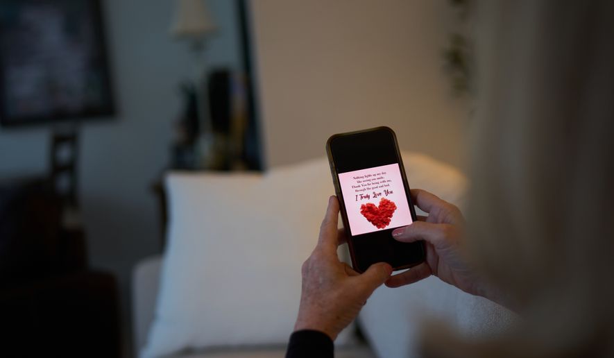 Debra Fox, who had $58,000 stolen from her in a romance scam, looks at a message on her phone that her scammer sent as she sits at home, Wednesday, May 13, 2026, in Arvada, Colo. (AP Photo/David Goldman)