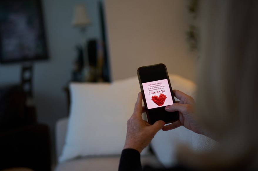 Debra Fox, who had $58,000 stolen from her in a romance scam, looks at a message on her phone that her scammer sent as she sits at home, Wednesday, May 13, 2026, in Arvada, Colo. (AP Photo/David Goldman)
